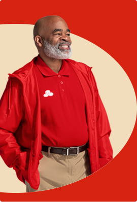 A bearded State Farm agent in red polo shirt and pullover smiles